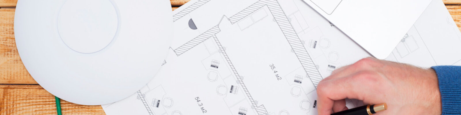 Engineering process. Man developing a network diagram for wifi access in cafe. Access point, floor layout, laptop and man hand on the bright background. Space for your text.